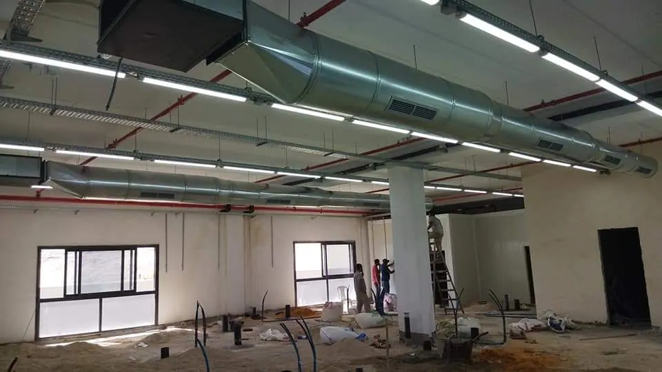 אולם מסחרי בשלבי גמר עם מערך תעלות ספירליות מגולוונות ותאורת פסים תלויה